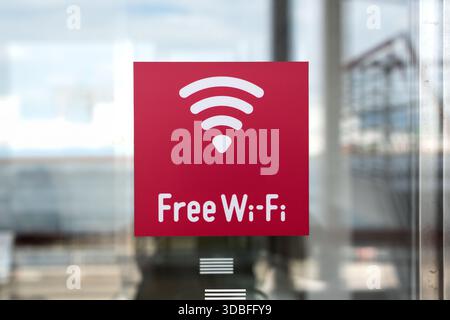 A vibrant red square sticker with a white Wi-Fi icon and "Free Wi-Fi" text displayed on a transparent glass surface. Stock Photo