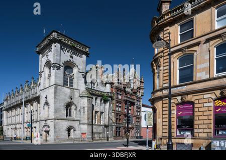Bright, sunny day highlights a historic stone building beside ornate red-brick architecture along a city street in Dundee, creating a timeless urban f Stock Photo