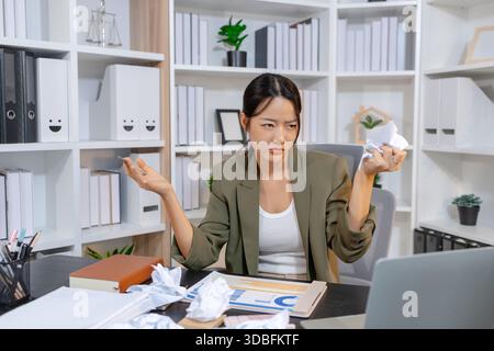 Stressed businesswoman dealing with heavy work pressure, reacting emotionally while reviewing reports and facing tight deadlines, highlighting workpla Stock Photo