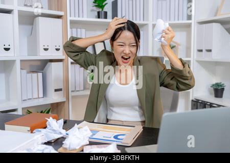 Stressed businesswoman dealing with heavy work pressure, reacting emotionally while reviewing reports and facing tight deadlines, highlighting workpla Stock Photo
