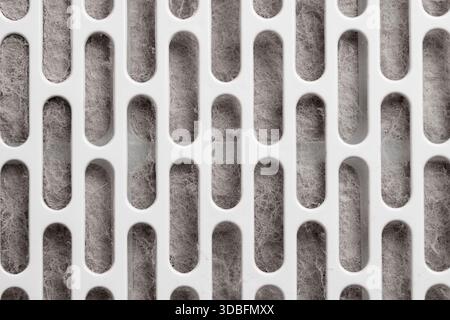 Abstract textured background of dirty fibrous air filtration material behind white plastic grille. Dusty surface. Minimal industrial design. Technical Stock Photo