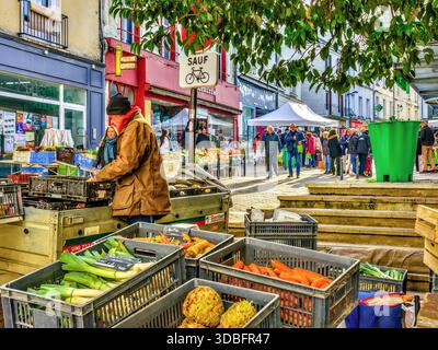 Busy market day with stallholder arranging vegetables on display - Chatellerault, Vienne (86), France. Stock Photo