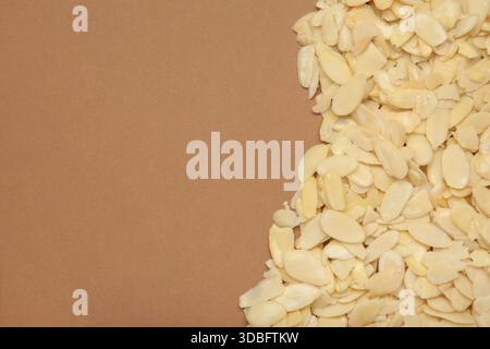 Fresh almond flakes on brown background, top view Stock Photo