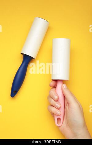 Woman holding lint roller on yellow background. Space for text Stock Photo