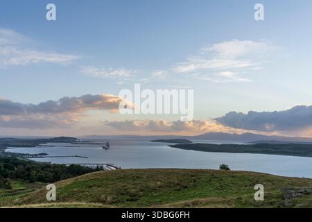View to Great Cumbrae and Little Cumbrae from a hillside above Largs, Scotland, at sunset over calm water. Stock Photo