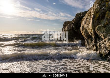 Dramatic coastal scene along the Girvan shore with rugged rocks, surf, and sunset light. Stock Photo