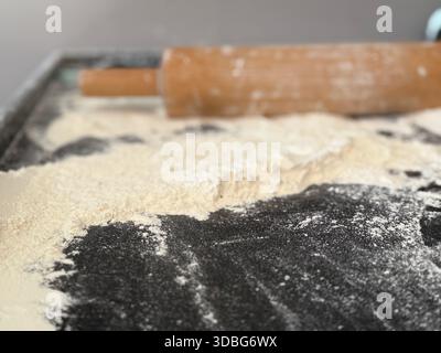 Rolling pin on floured counter top with flour spread around, suitable for baking background. Mobile photo Stock Photo
