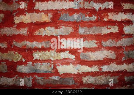 Close-up detail of an aged red brick wall with rough mortar and peeling surface Stock Photo