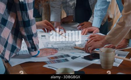 Creative casual informal business team group talking discuss building papers blueprint plan writing drawing communicate together five people diversity Stock Photo