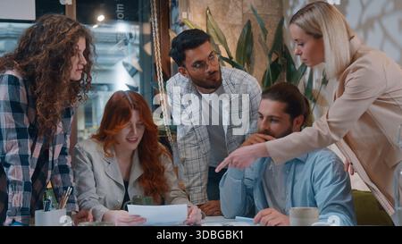 Casual informal business team five creative coworkers discussing papers documents in office startup project result paperwork talking together Stock Photo