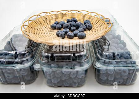 Fresh blueberries in wicker basket placed on plastic containers isolated on white background Stock Photo