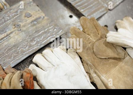 Worn gloves and metal plates on a workshop table showcase craftsmanship and dedication to skill Stock Photo