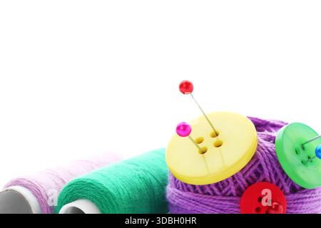 Ball of bright knitting yarn with buttons, spools of thread and pins on white background Stock Photo