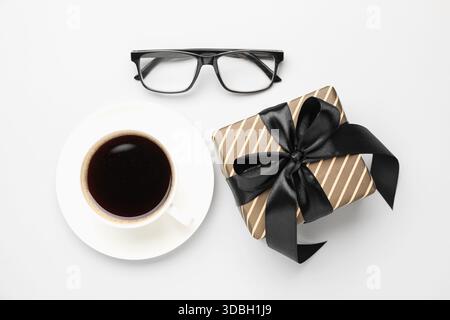 Beautiful gift box, glasses and cup of coffee on white background, flat lay Stock Photo
