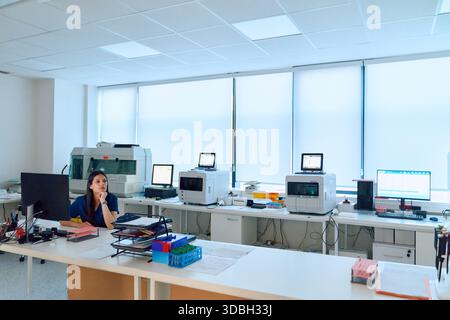 Scientist working in a modern laboratory setting with advanced equipment during the day Stock Photo