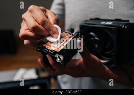 Computer technician cleaning processor cooling system with white cloth, ensuring optimal performance and preventing overheating during maintenance. Stock Photo