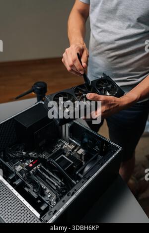 Vertical cropped shot of unrecognizable computer technician brushing graphics card, cleaning delicate electronic component for maintaining peak Stock Photo