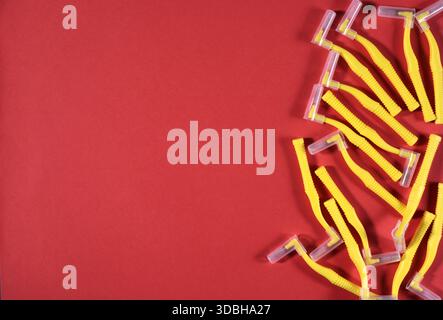 Image of yellow interdental brushes on a red background in the right side of the frame. Stock Photo