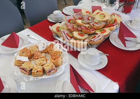 Reich gedeckter Tisch Ein üppiges Frühstück mit belegten Brötchen und Kuchen auf gedeckten Tischen in einem Restaurant *** Richly laid table A sumptuous breakfast with sandwiches and cakes on laid tables in a restaurant Stock Photo