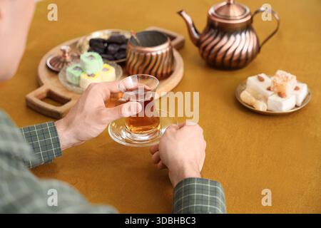 Young man with Turkish tea at table in kitchen, closeup Stock Photo