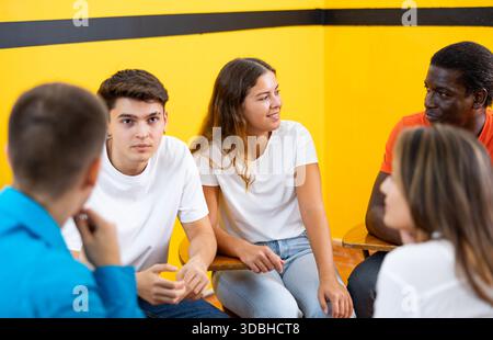 Friendly adult students chatting cheerfully while sitting in classroom Stock Photo