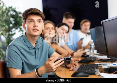 Excited young developer using mobile phone at IT startup presentation Stock Photo