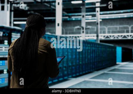 Engineer uses AI assistant to implement security measures, fortifying data center defenses against cyber threats. Server hub worker uses artificial intelligence to detect threats, defending systems Stock Photo