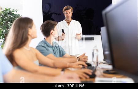 Experienced mentor explaining assigned tasks to young developers at IT startup Stock Photo