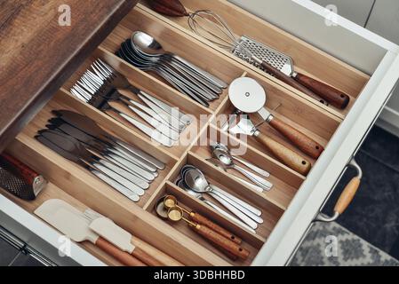 Bamboo organizer with cutlery in kitchen drawer, above view. Kitchen utensils storage. Stock Photo