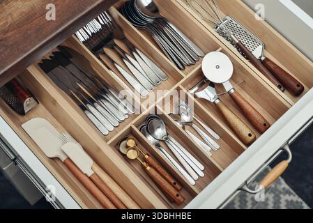 Bamboo organizer with cutlery in kitchen drawer, above view. Kitchen utensils storage. Stock Photo