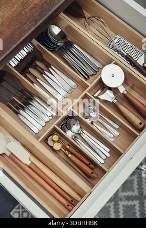 Bamboo organizer with cutlery in kitchen drawer, above view. Kitchen utensils storage. Stock Photo