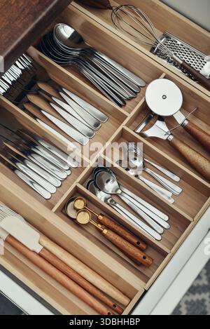 Bamboo organizer with cutlery in kitchen drawer, above view. Kitchen utensils storage. Stock Photo