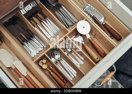 Bamboo organizer with cutlery in kitchen drawer, above view. Kitchen utensils storage. Stock Photo