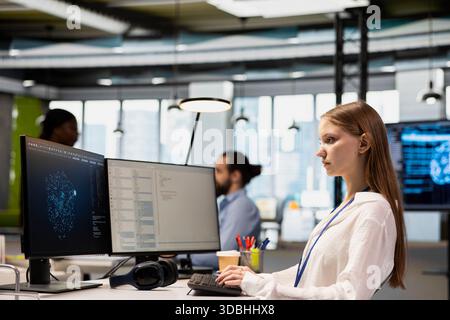 Female technician consulting AI LLM chatbot for tips on how to enhance system performance. Tech startup worker doing internship relying on AI assistant to automate manual tasks Stock Photo