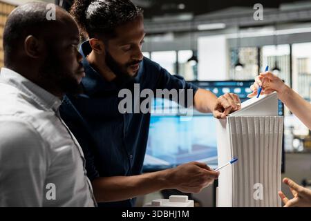 Engineers developers hold a strategic meeting for housing project through site planning and innovative design using architectural 3D models. Urban development master plan vision. Stock Photo