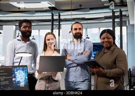 Portrait of happy teamworking programmers utilizing AI to optimize performance and forecast issues. Joyful coworkers in office training machine learning models using devices Stock Photo