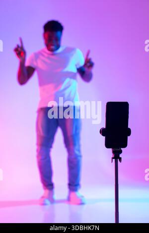 Black Male Influencer Enjoying Neon Lights While Creating Social Media Content Stock Photo