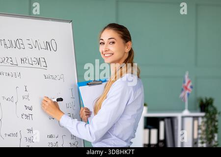 Cheerful Teacher Engaging Students in Online English Grammar Lessons From a Bright Classroom Stock Photo