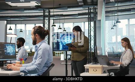 Female programmer coding AI algorithms on tablet to debug software issues and improving system stability. Woman in tech startup office configuring settings using device, camera A Stock Photo