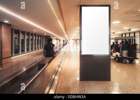Vertical mock-up lightbox display in modern airport corridor with travelator, motion blur silhouettes of travelers, dynamic movement, copy space scree Stock Photo