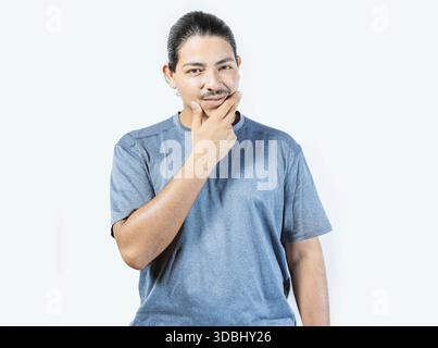Pensive person rubbing chin with doubtful expression. Thoughtful young man rubbing his chin looking at camera isolated Stock Photo