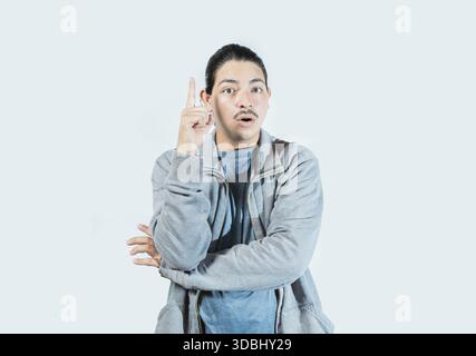 Surprised guy pointing a promotion up isolated. Surprised asian man pointing a discount up on isolated background Stock Photo