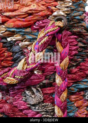 SEATTLE - APR 23, 2025 - Colorful strips of patterned fabric woven together with a golden rope, creating a vibrant and textured textile art piece with Stock Photo