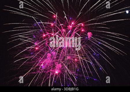 Colorful fireworks explode in the night sky over Huntington Beach, California, celebrating a festive event with bright trails and vibrant light. Stock Photo