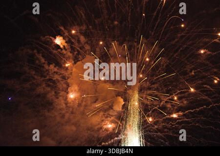 Golden fireworks erupt in the night sky over Huntington Beach, California, with glowing sparks and smoke capturing a dramatic festive moment. Stock Photo