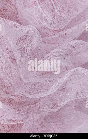 Chic vertical background of white airy guipure with floral ornaments. soft folds of transparent white fabric on a pink background. wedding concept Stock Photo