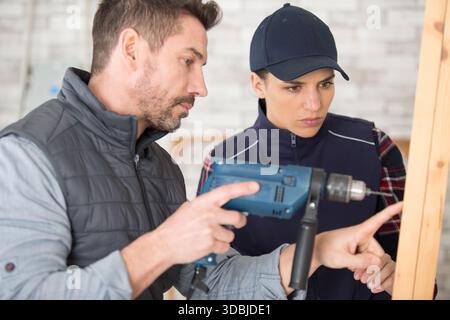 carpenter woman and man with drill in workshop Stock Photo
