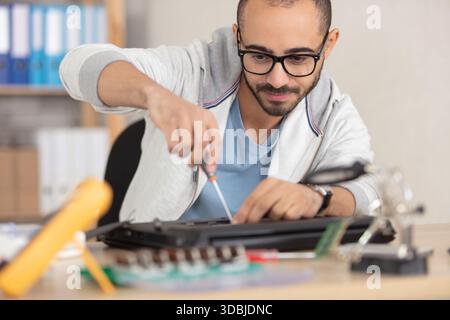 man repairing his laptop using a screwdriver Stock Photo
