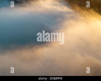 Aerial view of a golden sun kissing the crisp, swirling fog, a ethereal dance of light and shadow over the Thames Valley, Oxfordshire, United Kingdom. Stock Photo