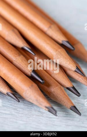 wooden pencils with black lead on blue corrugated paper, monochrome pencils for sketches or graphic work are in a row. Stock Photo